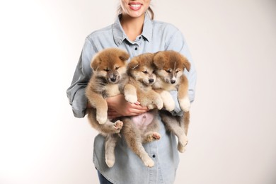 Woman holding Akita Inu puppies on light background, closeup