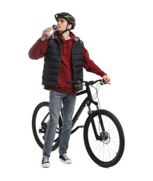 Man in helmet with bicycle drinking water on white background