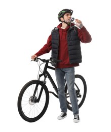 Man in helmet with bicycle drinking water on white background