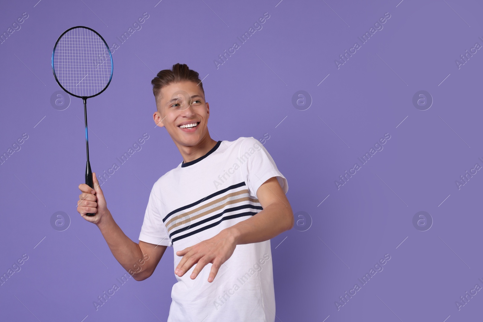 Photo of Young man playing badminton with racket on purple background