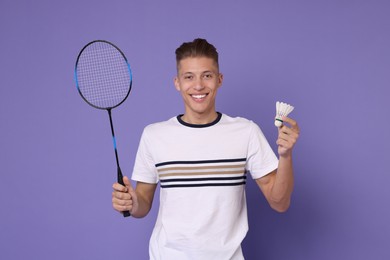 Young man with badminton racket and shuttlecock on purple background