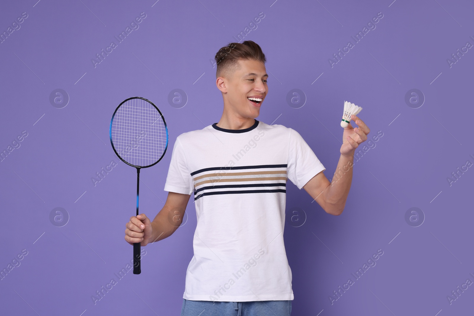 Photo of Young man with badminton racket and shuttlecock on purple background