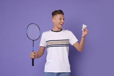 Photo of Young man with badminton racket and shuttlecock on purple background