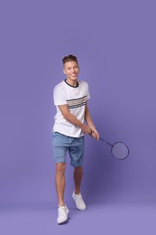 Photo of Young man playing badminton with racket on purple background