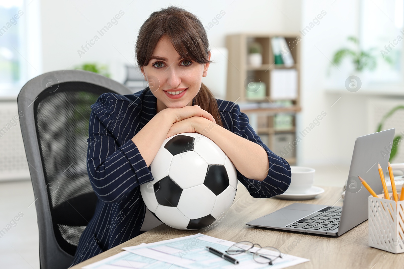 Photo of Smiling employee with soccer ball at table in office