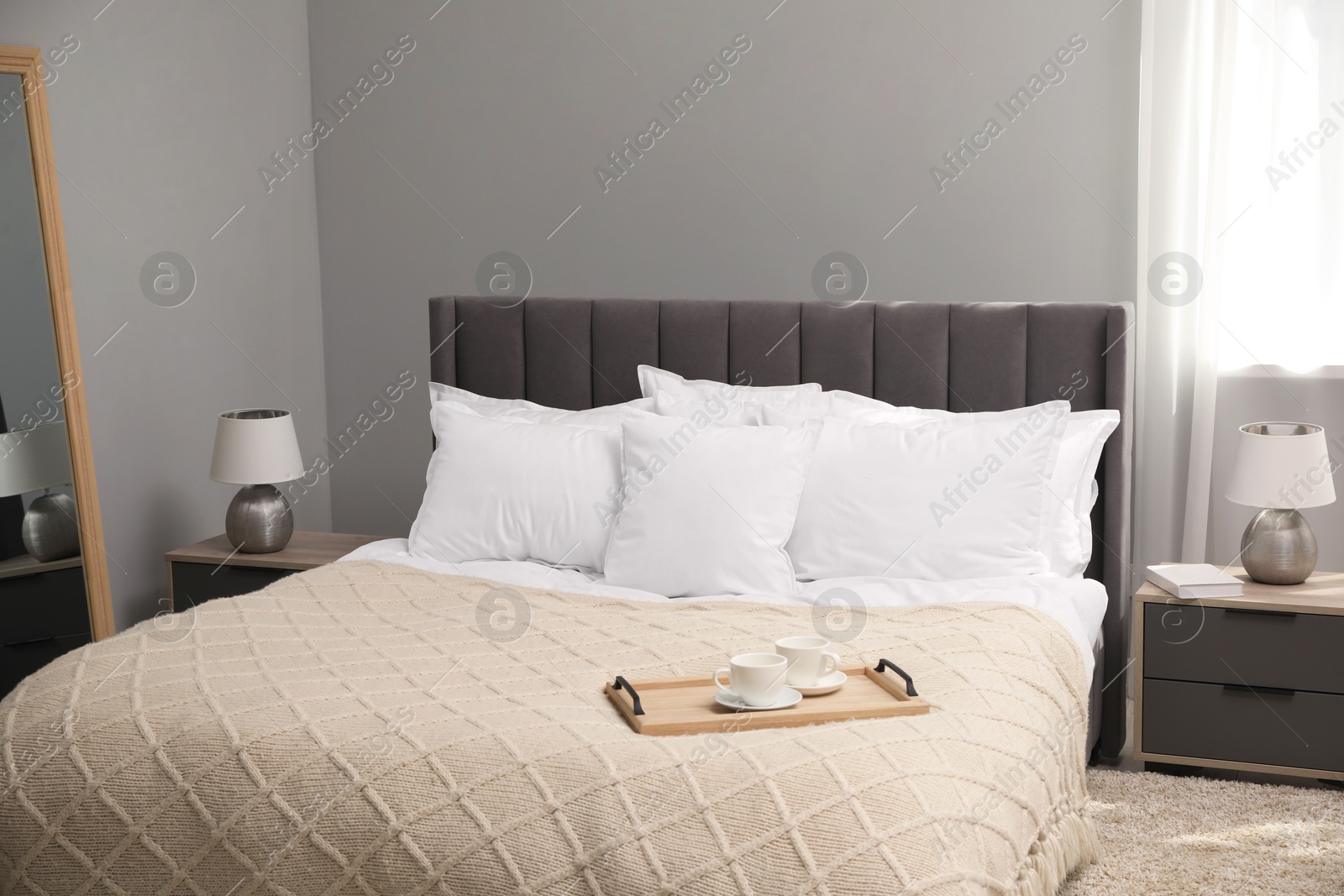 Photo of Many soft white pillows and knitted blanket on bed indoors