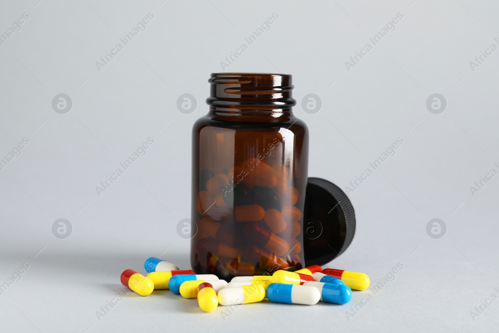 Photo of Antibiotic pills and bottle on grey background. Medicinal treatment