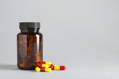 Photo of Antibiotic pills and bottle on grey background, space for text. Medicinal treatment