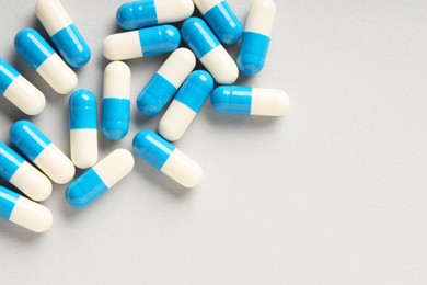 Photo of Many antibiotic pills on grey background, top view and space for text. Medicinal treatment