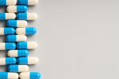 Photo of Many antibiotic pills on grey background, top view and space for text. Medicinal treatment