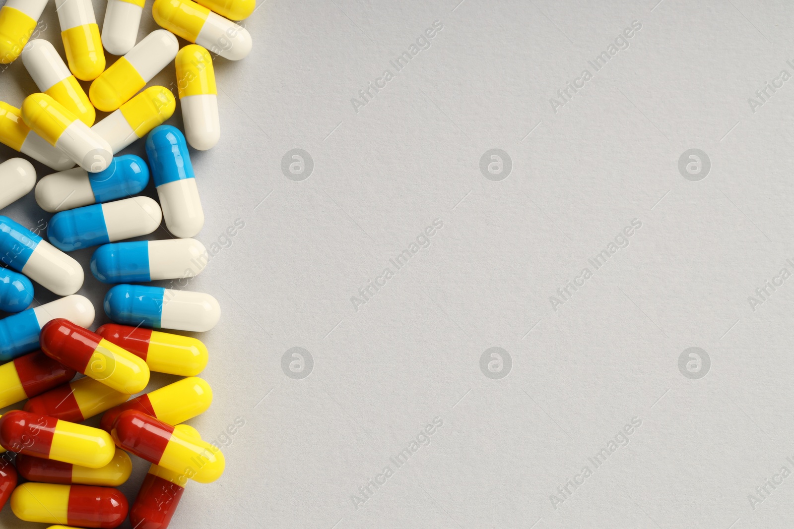 Photo of Many antibiotic pills on grey background, top view and space for text. Medicinal treatment