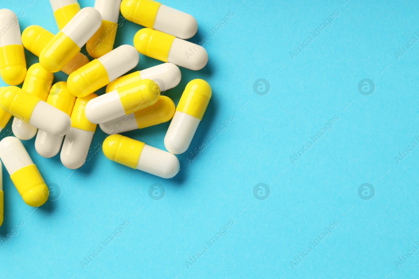 Photo of Many antibiotic pills and space for text on light blue background, top view. Medicinal treatment