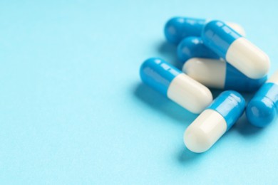 Photo of Many antibiotic pills on light blue background, closeup. Medicinal treatment