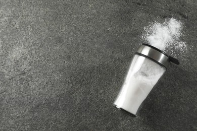 Photo of Salt shaker on grey textured table, top view. Space for text