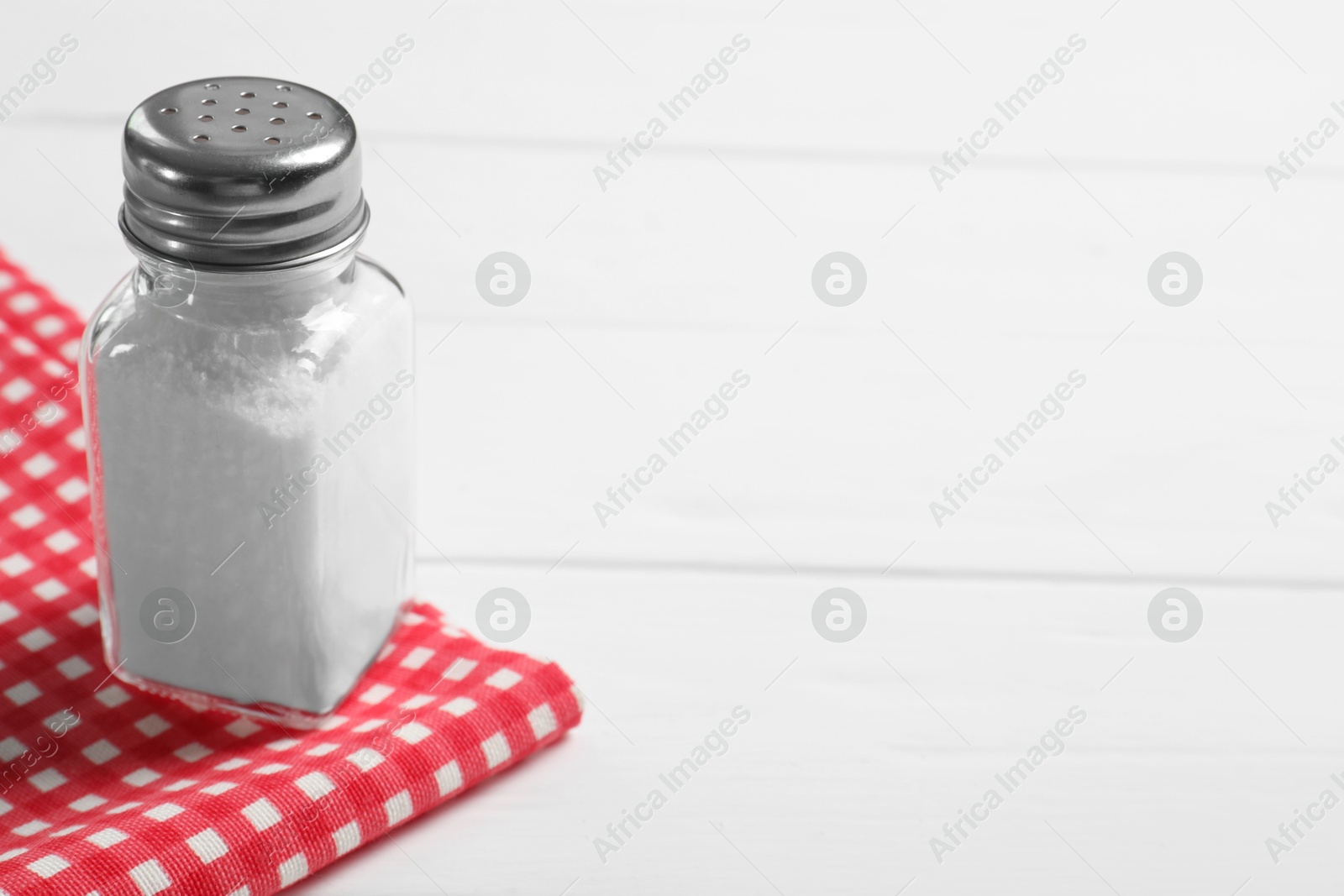 Photo of Salt shaker on white wooden table. Space for text