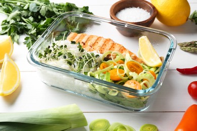 Photo of Healthy meal. Salmon, rice and salad in container near other products on white wooden table