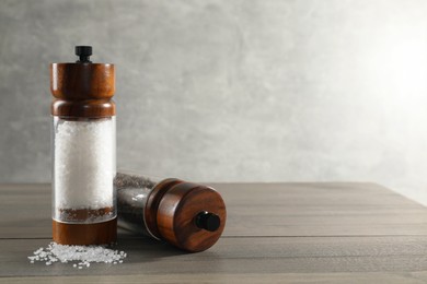 Photo of Salt and pepper shakers on wooden table, space for text