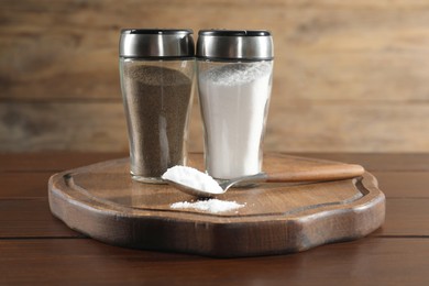 Photo of Salt and pepper shakers on wooden table, closeup