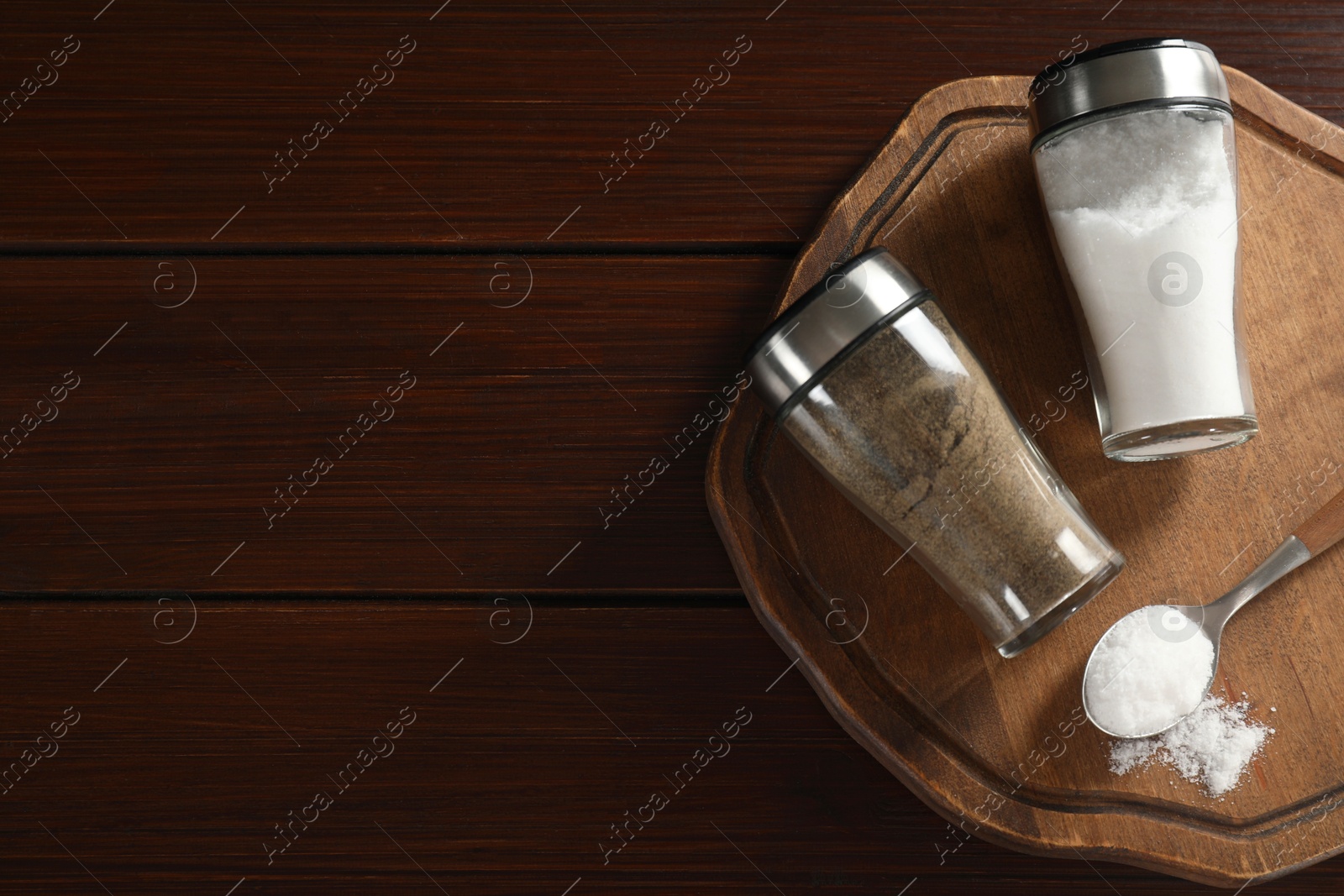 Photo of Salt and pepper shakers on wooden table, top view. Space for text