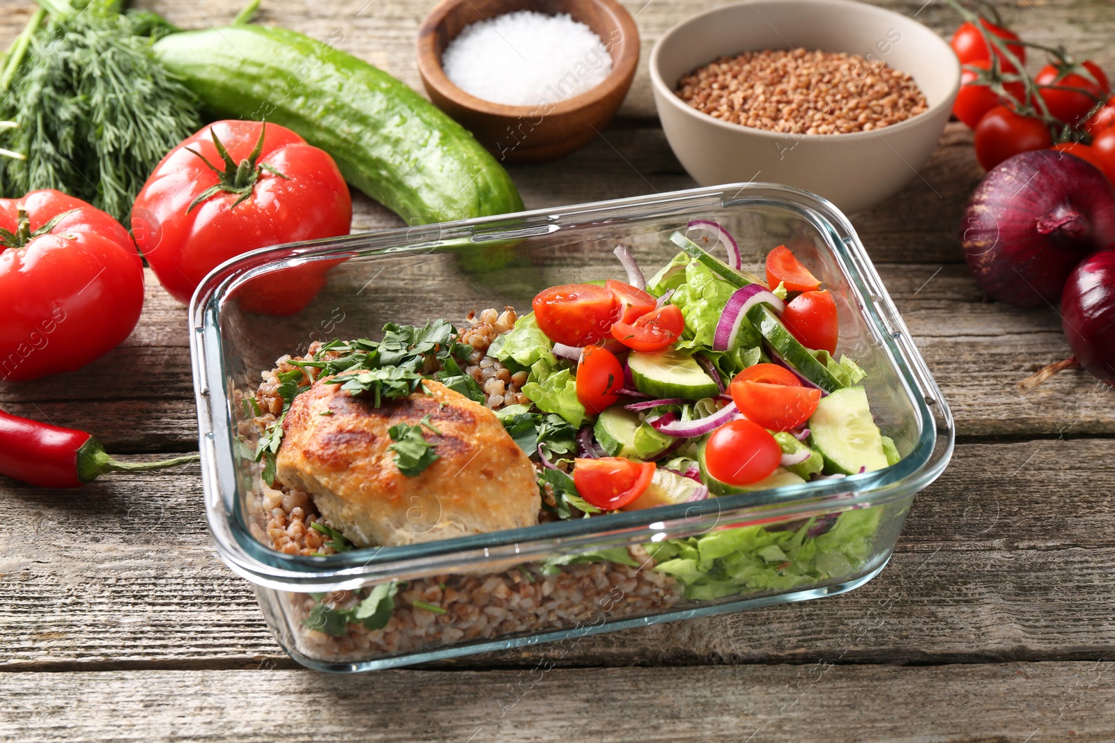 Photo of Healthy meal. Cutlet, buckwheat and salad in container near other products on wooden table