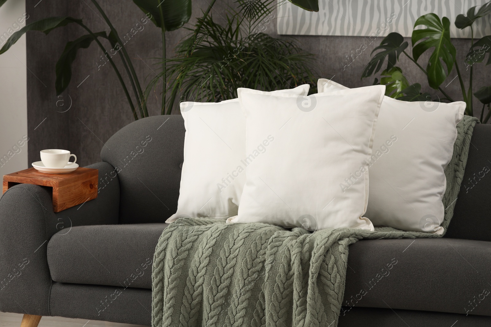 Photo of Soft white pillows and blanket on sofa indoors