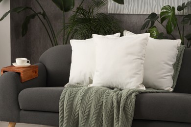 Photo of Soft white pillows and blanket on sofa indoors