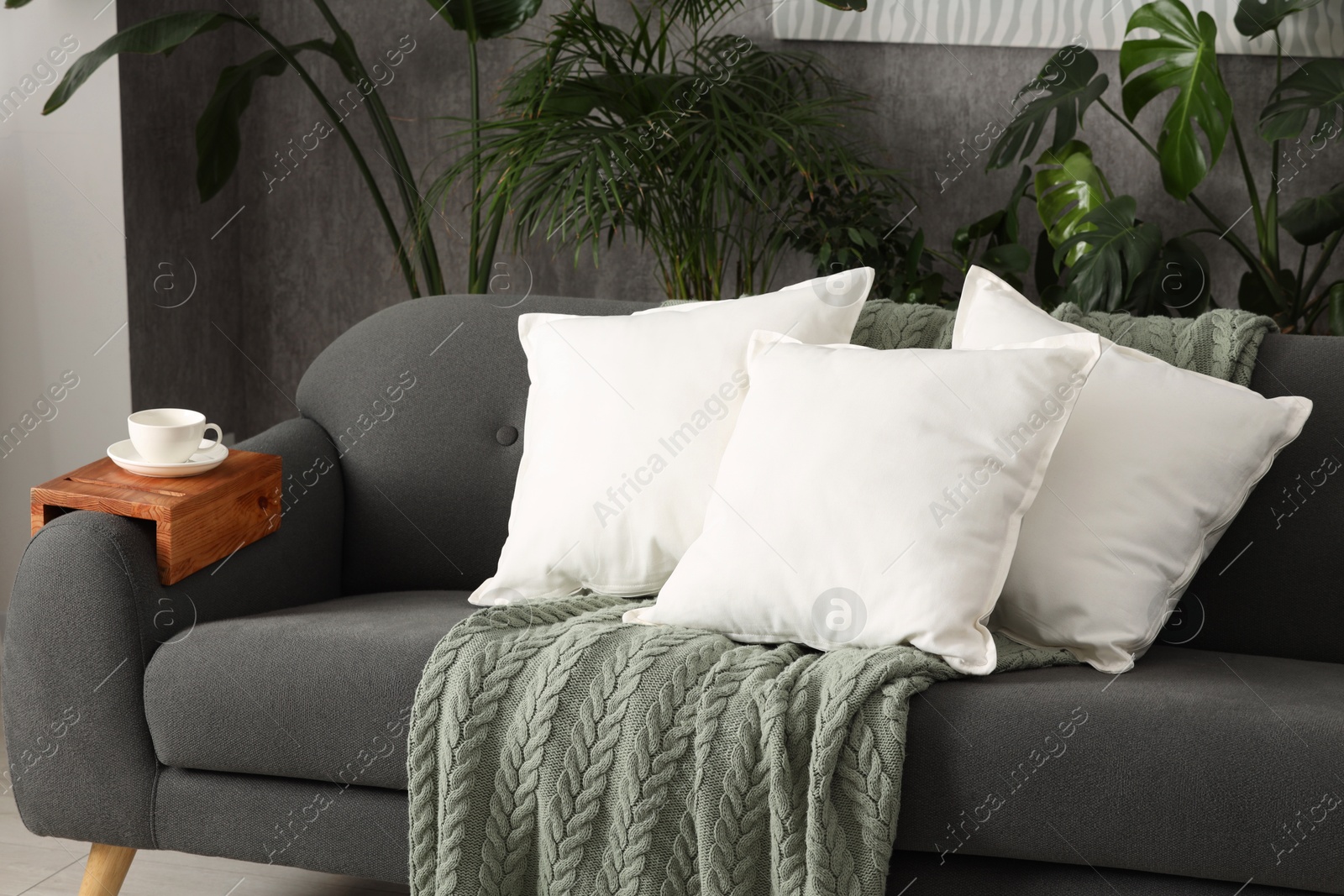 Photo of Soft white pillows and blanket on sofa indoors