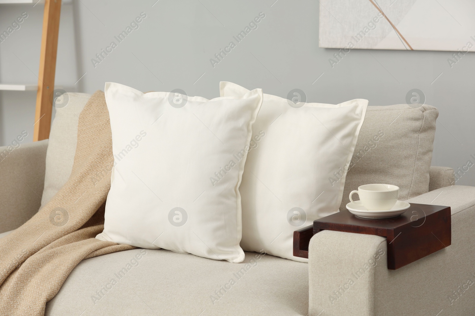 Photo of Soft white pillows and blanket on sofa indoors