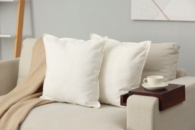 Photo of Soft white pillows and blanket on sofa indoors