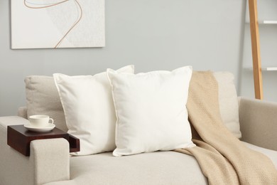 Photo of Soft white pillows and blanket on sofa indoors