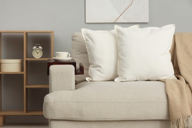 Photo of Soft white pillows and blanket on sofa indoors