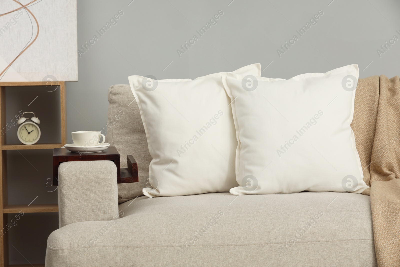 Photo of Soft white pillows and blanket on sofa indoors