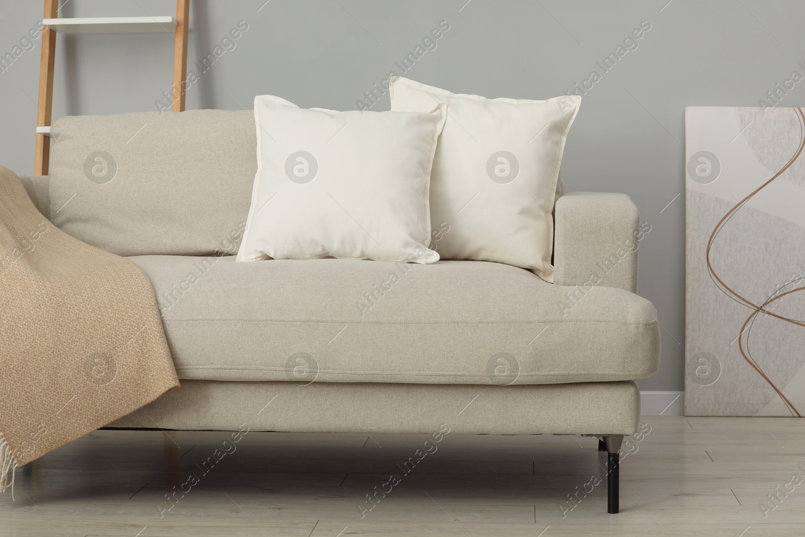 Photo of Soft white pillows and blanket on sofa indoors