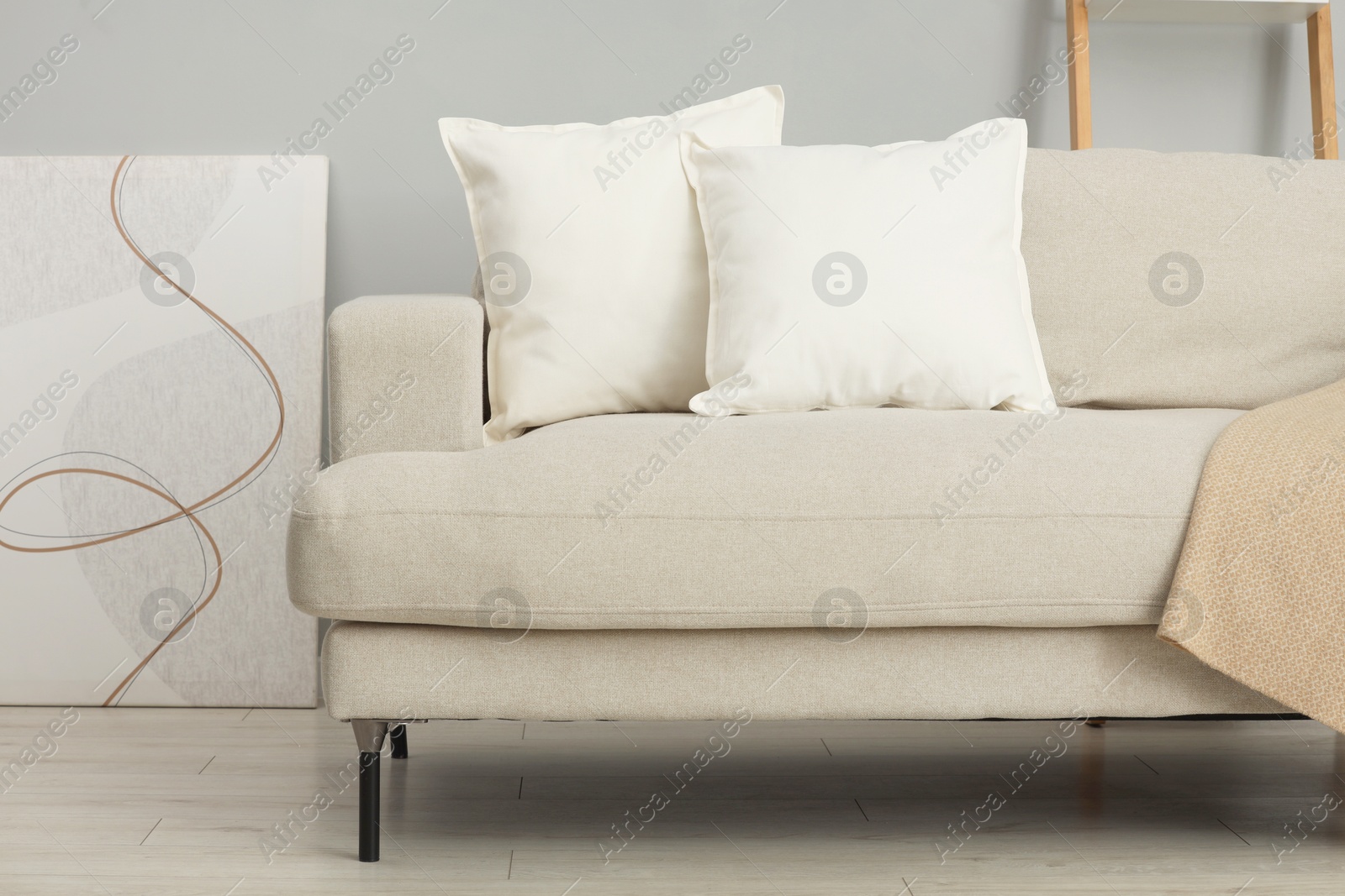 Photo of Soft white pillows and blanket on sofa indoors