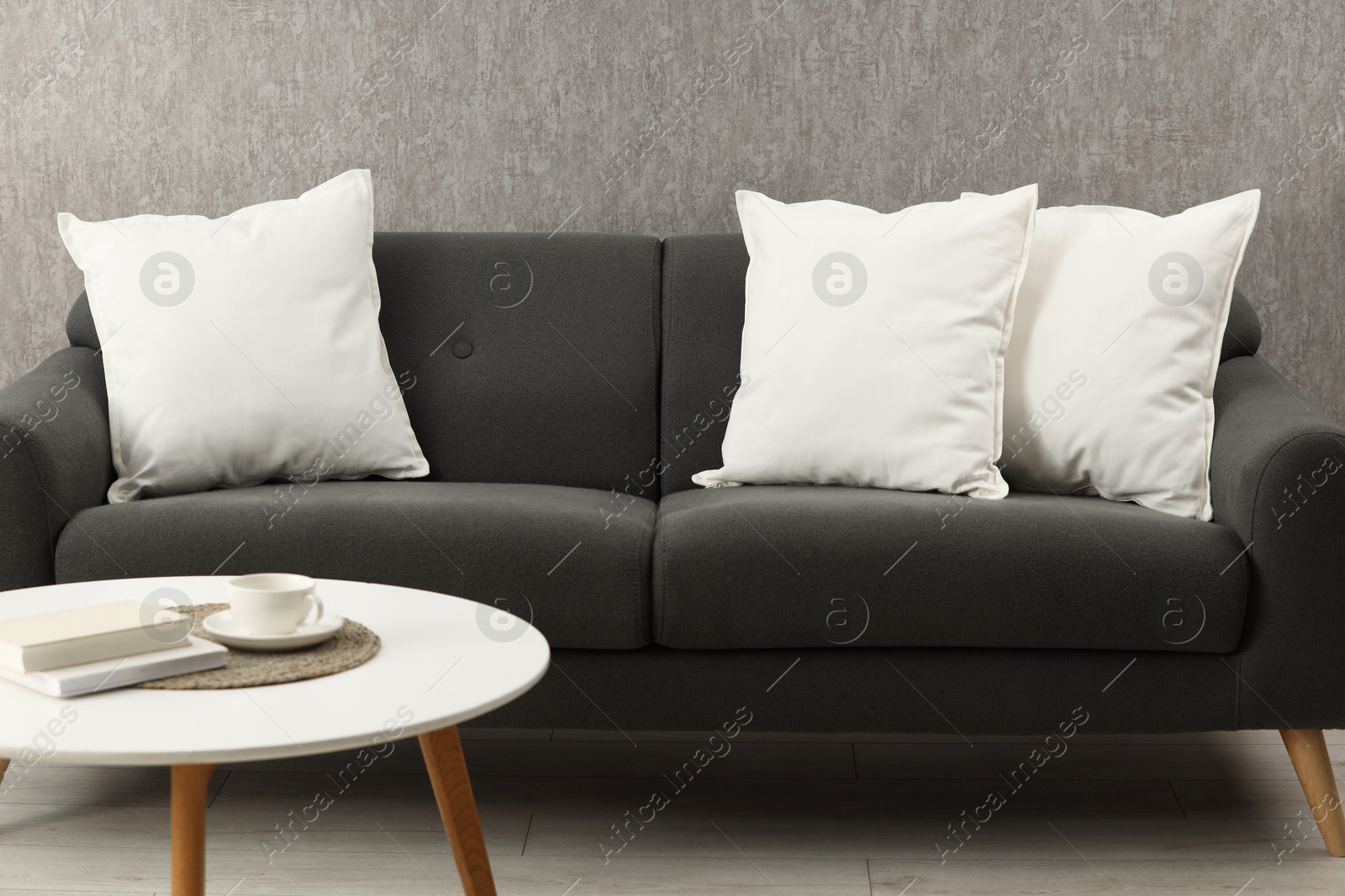 Photo of Soft white pillows on sofa and coffee table indoors