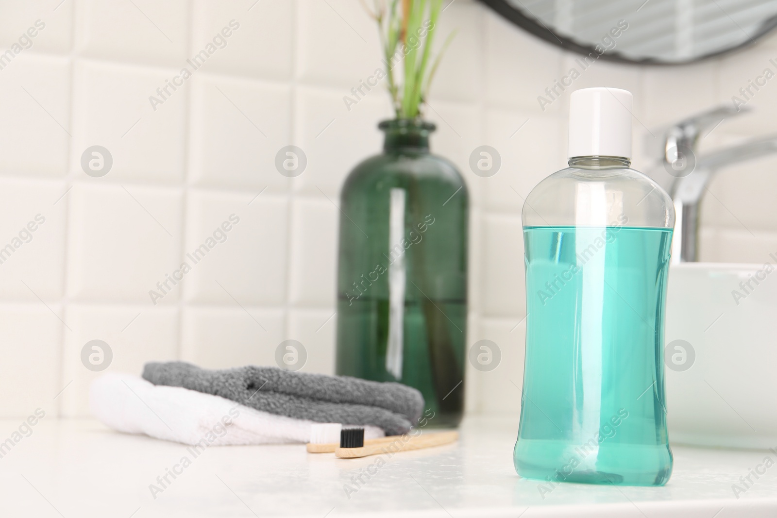 Photo of Bottle of mouthwash on white table in bathroom, space for text