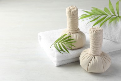 Photo of Spa composition. Herbal bags, towels and palm leaves on light table, space for text