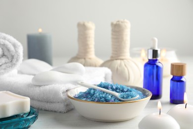 Photo of Spa composition. Cosmetic products, soap, towels, sea salt and burning candles on light table