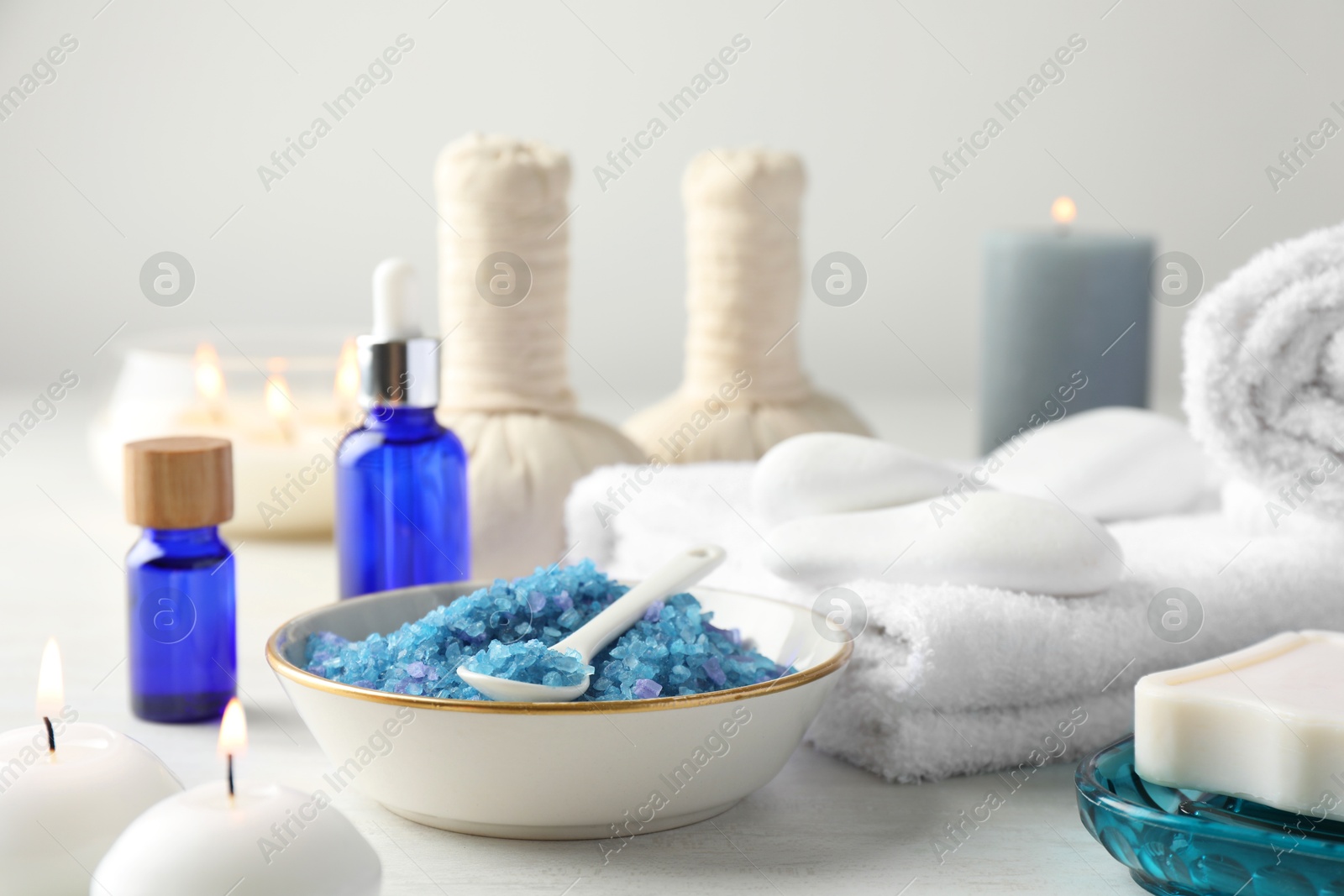 Photo of Spa composition. Cosmetic products, soap, towels, sea salt and burning candles on light table