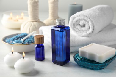 Photo of Spa composition. Cosmetic products, soap, towels, sea salt and burning candles on light table