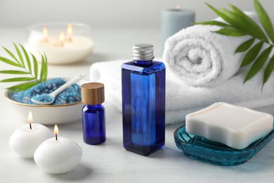 Photo of Spa composition. Cosmetic products, soap, towels, sea salt and burning candles on light table