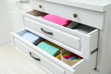 Chest of drawers with different folded clothes indoors