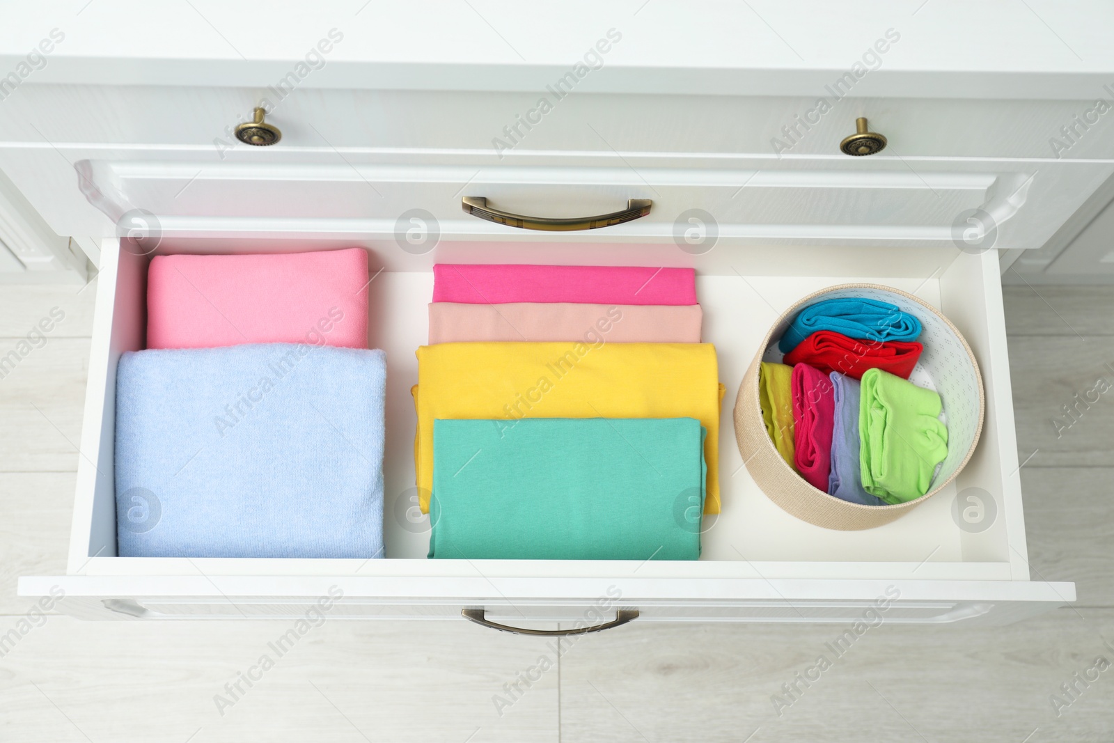 Photo of Chest of drawers with different folded clothes indoors, top view