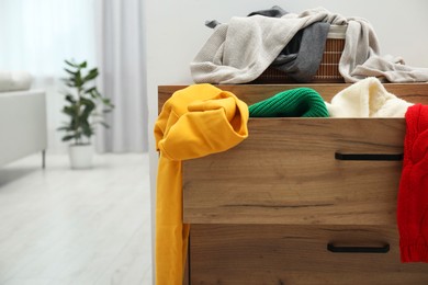 Cluttered chest of drawers indoors, space for text. Clothes in mess