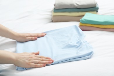 Photo of Woman folding clothes on bed, closeup view