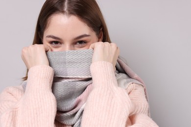 Photo of Beautiful woman in warm scarf on gray background, space for text