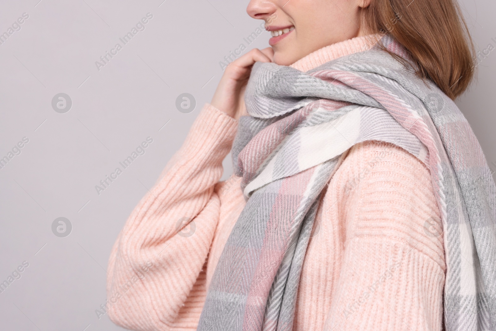 Photo of Woman in warm scarf on gray background, closeup. Space for text
