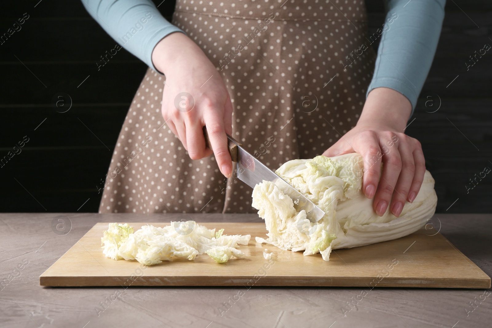 Photo of Healthy food. Woman cutting Chinese cabbage at grey table, closeup