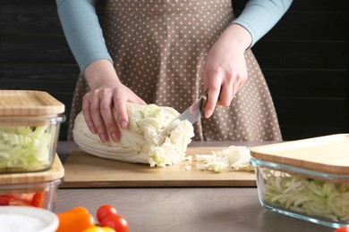 Photo of Healthy food. Woman cutting Chinese cabbage at grey table, closeup