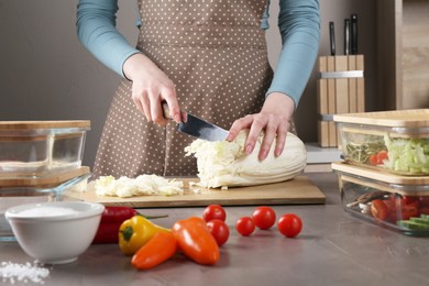 Photo of Healthy food. Woman cutting Chinese cabbage at grey table, closeup